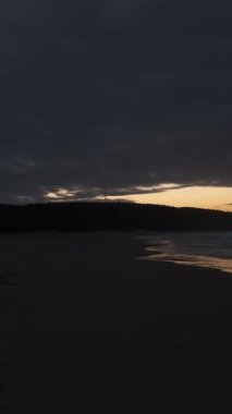 Bulutlu günbatımında şehrin koşuşturmasından kaçan adam plajda spor yapıyor.