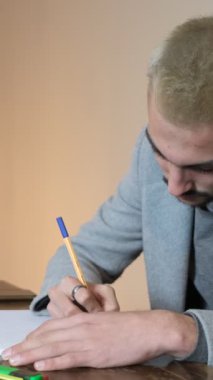 Genç adam renkli kalemlerle notlar alıyor, çok çalışırken fosforlu kalemler alıyor, kağıtlara duygular ve düşünceler yazıyor.