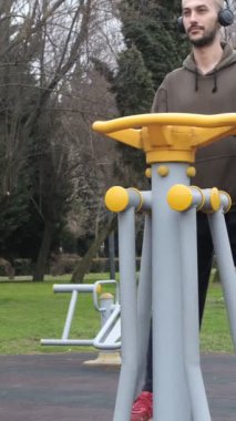 Kamu spor ekipmanları üzerine spor yapmak, gençlerin şehir parklarında müzik dinlerken sağlık faaliyetleri yapmak.