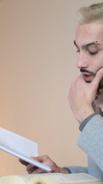 Genç adam içeride masasında kitap okuyor, yazılı belgeyi dikkatlice inceliyor, dudağıyla kitap okurken...
