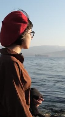 Genç, güzel bir kadın işten sonra deniz kenarındaki koşu bandında dinleniyor, akşam kumsalda geziniyor, şapkalı bir kadın görüntüsü yürüyüşe çıkıyor.