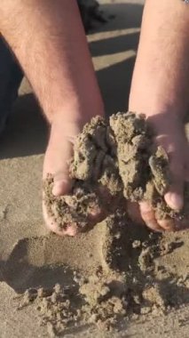 Kumu kavrayan insan eli, kumla oynayan insan görüntüsü, kumsalda zaman geçiren insan.