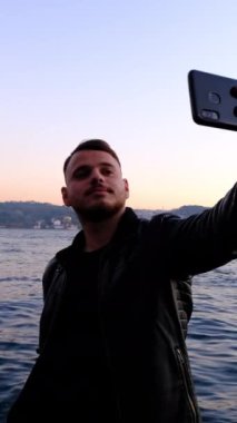 İstanbul Boğazı 'yla birebir selfie çekmek isteyen genç adam temalı bir resim.