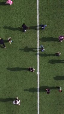 Yeşil bir futbol sahasında oynayan büyük bir grup çocuğun havadan görünüşü. Astroturf 'ta oynayan erkeklerin yukarıdan görünüşü.