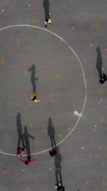 Özel bir parkta top oynayan maskeli erkek ve kızların, halıda oynayan çocukların drone görüntüleri.