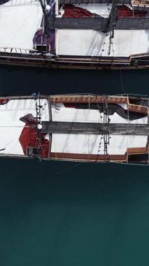  Marinada demirlemiş teknelerin hava aracı görüntüsü, turkuaz sularda duran teknelerin yukarıdan görünüşü.