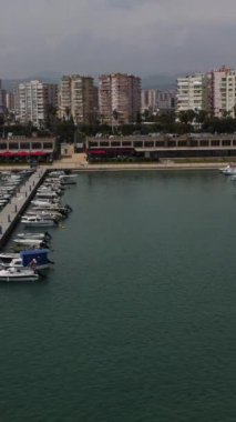 Yat limanına demirlemiş teknelerin ve kano kullanan insanların havadan görünüşü, şehir sahilindeki marinanın yukarıdan görünüşü.