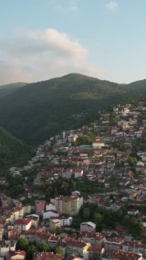 Aerial city in green valley, bursas cultural architecture and city settlement drone view, beautiful turkish city built at the foot of green forested mountains