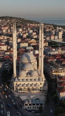 Bina arasındaki caminin havadan görünüşü, cami bahçesinde namaz kılan insanlar, oturma alanlarındaki dini binalar.