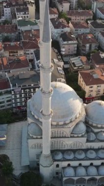 Binalar arasındaki cami manzarası, cami bahçesinde namaz kılan insanlar, oturma alanlarındaki dini binalar.