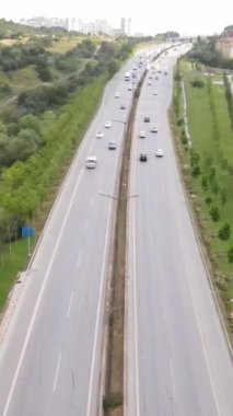 Yol boyunca az sayıda araç ve yolcu bulunan orman ve ağaçların bulunduğu İHA hava yolu manzarası, İstanbul ve Türkiye 'deki yeşil santrallerle çevrili yol işaretli şehir caddesi, yüksek kaliteli