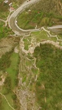 Şehirdeki dağın tepesine inşa edilmiş eski tarihi şatonun havadan görünüşü, yeşil tepedeki eski şato kalıntıları.