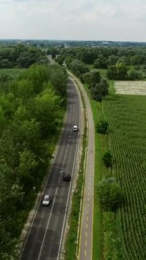 Ağaçlar ve kırsal alanla çevrili bir otoyolun iki tarafını gösteren hava manzarası, tarım arazileri arasındaki yol trafiği.