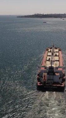 Deniz kıyısında bir şehir olan Boğaz 'ı geçen büyük bir nakliye gemisinin hava görüntüsü, iki tarafı birbirine bağlayan bir köprü.
