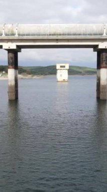 Baraj gölü barajı su havuzu manzarası, gölet barajının üzerindeki köprü, su birikintisi, bulutlu gökyüzü, barajın içindeki yapı, doğal çevre.