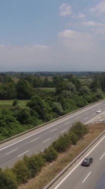 Her iki tarafında kırsal alan olan asfalt yolu, yeşil ağaçların arasından geçen şehirlerarası yol.
