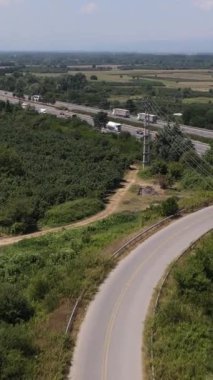 Her iki tarafında kırsal alan olan asfalt yolu havadan görünüyor. Şehirlerarası yol köylerden geçiyor.