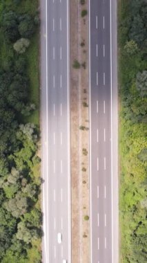 Her iki tarafında kırsal alan olan asfalt yolu, yeşil ağaçların arasından geçen şehirlerarası yol.