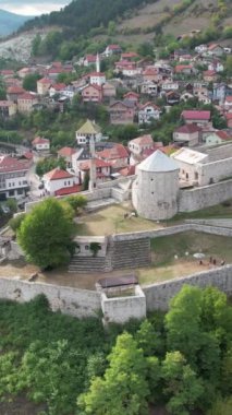 Tarihsel ortaçağ şatosunun insansız hava aracı görüntüsü, dağ yamacına tünemiş antik taş kale manzarası, surlar ve gözetleme kuleleriyle çevrili yapı
