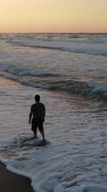 Gün batımında kumsalda romantik bir yürüyüş. Hava aracı uçurmak. Akşamları sahilde yürüyen bir adamın silueti.