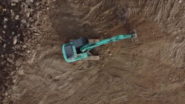 Uzun çalışma günleri boyunca bahçedeki toprakla çalışan kazıcının hava görüntüsü, tarım arazilerinde çalışan makine.