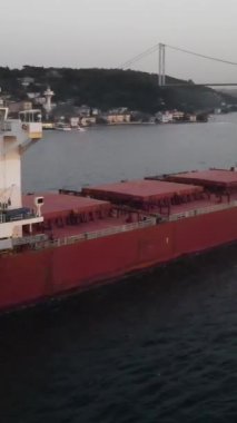 Boğazdan geçen boş bir konteyner gemisinin drone görüntüsü, deniz kenarı, deniz kenarı, büyük köprü manzarası.