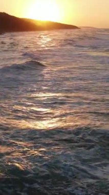 Mavi enerjinin ve berrak okyanus suyunun canlılığı, yukarıdan aşağıya dron çekim perspektifindeki güçlü fırtınalı deniz dalgaları, köpüklü beyaz dokuyla denizdeki dalga çizgilerini çarpıştırmak.