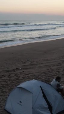 Sabahları deniz kenarında güneş ışığına karşı kamp çadırı. Arka planda Dji hava aracı manzarası yüksek kaliteli.