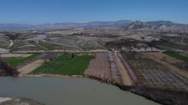 Nehirle inşa edilmiş tarım arazilerinin havadan görünüşü, sabanla sürülmüş tarım arazilerinin ve dağların manzarası, bahar manzarası.