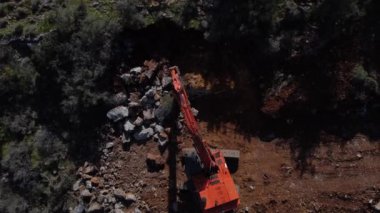 Ormandaki taş ve çalıları kaldırarak yol çalışması yapan turuncu toprak taşıma makinesinin yukarıdan görünüşü, yol çalışması yapan makinenin havadan görüntüsü