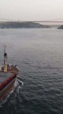 Boğaz 'da bir gemi, deniz kenarında inşa edilmiş güzel bir şehir, Boğaz' ı geçen köprüyü görüyor.