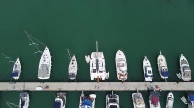 Güzel bir günde limana demirlemiş yatların insansız hava aracı manzarası park etmiş yelkenlilerin ve teknelerin tepeden görünüşü.