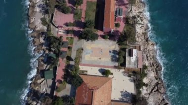 Güneşli bir günde deniz kenarındaki tatil köyünün tepedeki manzarası deniz kenarındaki butik otel dalgaların kıyıya vurduğu kayalıklara kurulmuş tatil yeri.