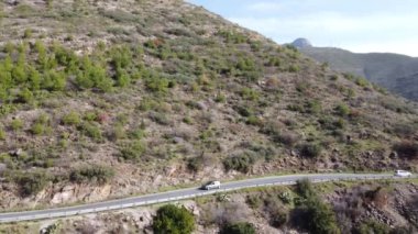 Dağın eteklerinden geçen trafiğin hava görüntüsü, dağ yolundan gelen bir çok araba ve kamyonun görüntüsü.