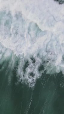 Mavi enerjinin ve berrak okyanus suyunun canlılığı, güçlü fırtınalı deniz dalgaları yukarıdan aşağıya dron çekim perspektifi, köpüklü beyaz dokuyla denizdeki dalga çizgisini çarpıştırıyor.
