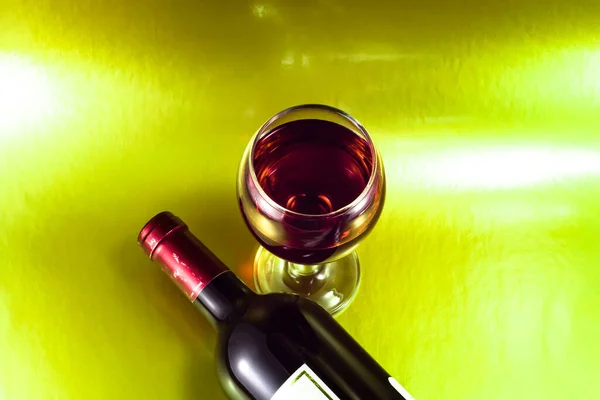 绿色抽象背景下的红葡萄酒瓶和酒杯 — 图库照片