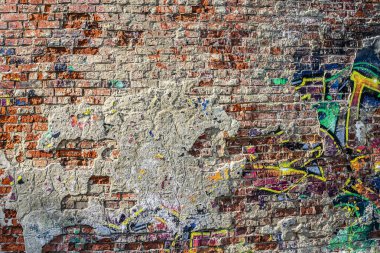 Soyut bir arkaplan olarak duvarda tanımlanamayan grafitiler var..