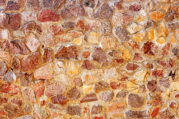 stock image A wall of granite stones in a warm color as a backdrop for your design.