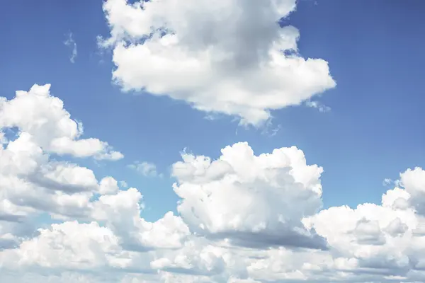 Arkaplan olarak mavi gökyüzünde beyaz kümülüs bulutları.