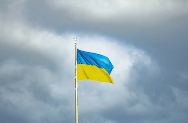 Ukrayna bayrağı rüzgarlı havada karanlık bir gökyüzünün arka planında.