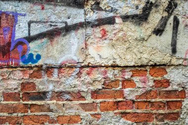 Eski kabuklu tuğla duvar. Duvar dokusu arka planında alçı ve grafiti kalıntıları var..