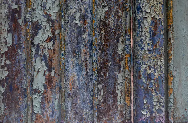 Soyut bir arkaplan olarak boyanmış metal bir çitten eski boyaların soyulması.