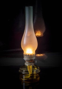 Siyah ayna arka planında cam bir ampulde eski bir gaz lambası..