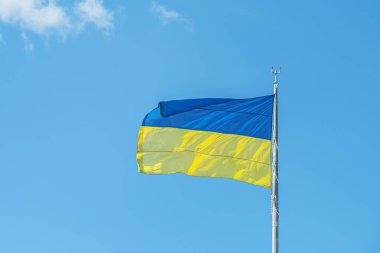 Ukrayna bayrağı açık mavi gökyüzüne karşı rüzgarda dalgalanıyor..