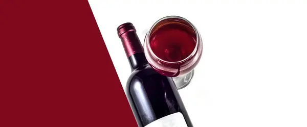 Beyaz arka planda cam ve bir şişe kırmızı şarap. Kırmızı arkaplan ve beyaz arkaplan - metin için yer.