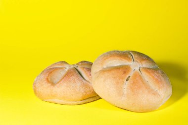 Two round breads fresh from oven on a yellow background.