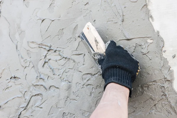 Decorative plaster coating, master makes the texture of venetian plastering on the wall with trowel, hand with trowel