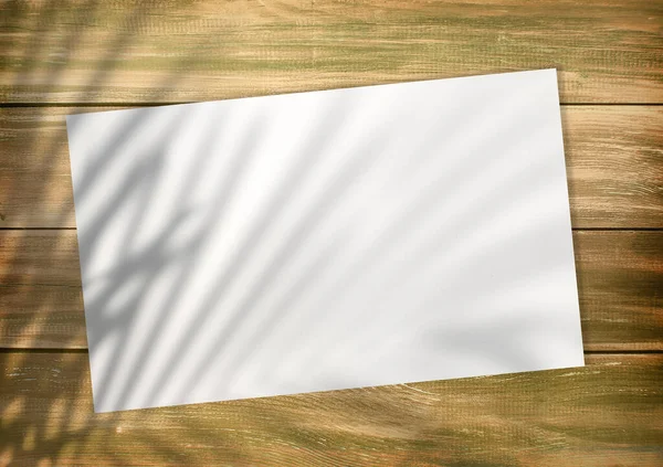 Empty white list on an old style wooden empty background with plam leaf shadow on it, top wiev