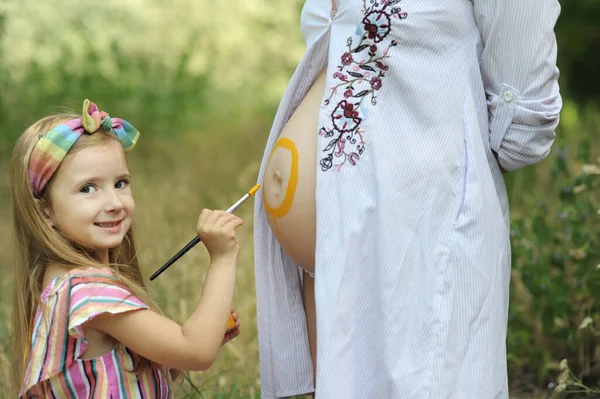 Mała Dziewczynka Maluje Słońce Brzuchu Ciężarnej Mamusi Świeżym Powietrzu Parku — Zdjęcie stockowe