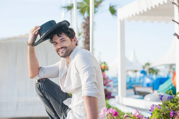 黒い帽子と白いシャツを着たハンサムな幸せな男 熱帯都市の風景に対する屋外の写真 — ストック写真
